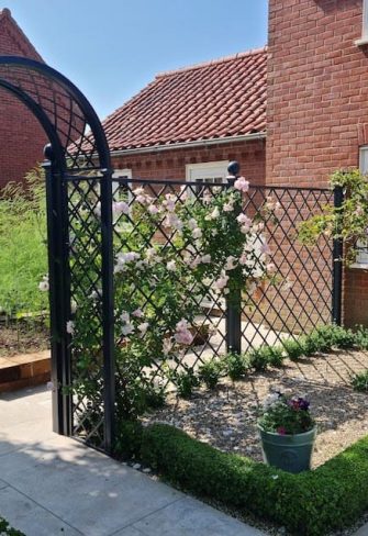 Classic Garden Elements' Portofino Romanesque Garden Arch and Paravent Metal Railing Panel on a sunny day