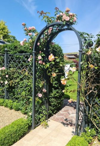 The Portofino Romanesque Garden Arch by Classic Garden Elements covered in roses