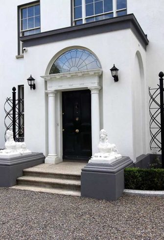 The stately Charleston Rose Obelisk by Classic Garden Elements in front of a Georgian mansion