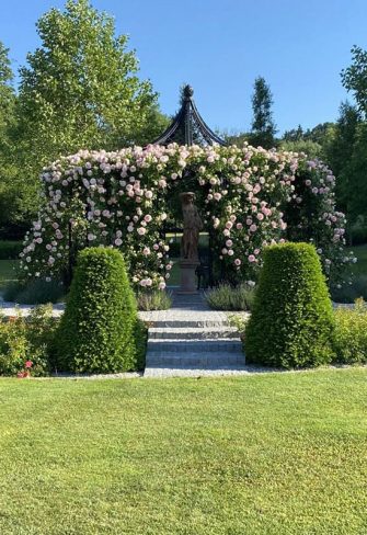 The Schoenbrunn Wrought-Iron Gazebo by Classic Garden Elements covered in blossom