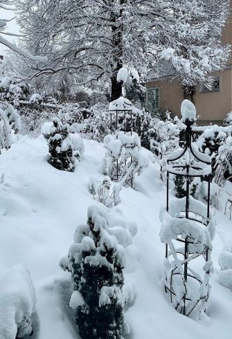 Three snow-covered Classic Garden Elements obelisks in a garden in Zurich