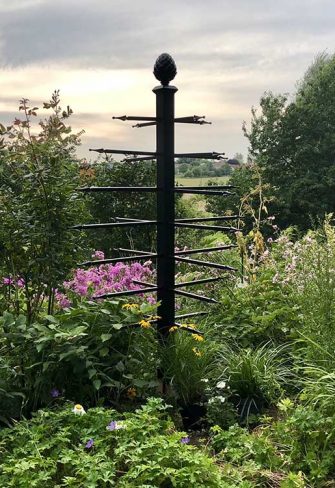 The freestanding Geneva Garden Obelisk by Classic Garden Elements surrounded by plants