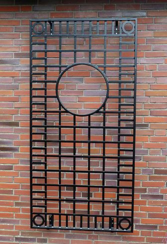 The Knebworth House Metal Wall Trellis by Classic Garden Elements installed on a red-brick wall