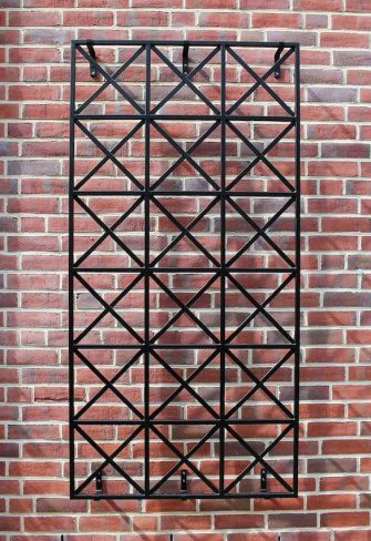 The Ravenna Metal Wall Trellis by Classic Garden Elements mounted on a brick wall