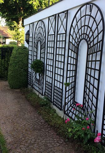 The Croome Treillage Panel Set by Classic Garden Elements installed on a white garden wall