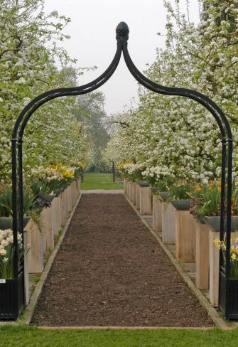 Freestanding Brighton Garden Arch with two Versailles Planters in an orchard in full bloom