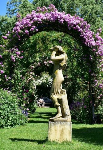 Portofino Romanesque Rose Arch with two planters, providing growing support to a 'Mannington Mauve Rambler' by Peter Beales