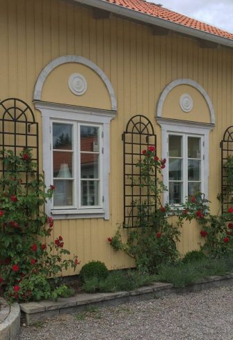 Three black Orangery Wall Trellises by Classic Garden Elements, on a yellow house wall in Sweden