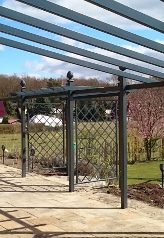 A bespoke Piemont Metal Pergola by Classic Garden Elements with side trellis panels