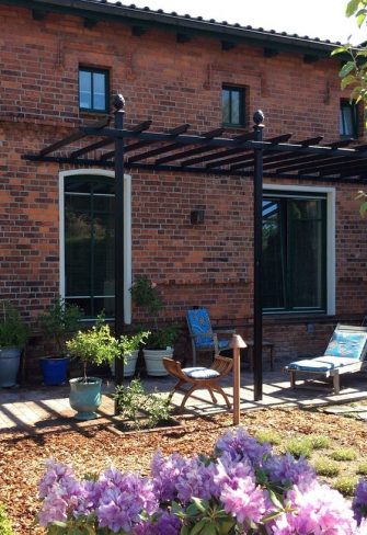 The Piemont Metal Pergola installed against a red-brick house