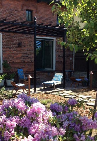 The Piemont Metal Pergola by Classic Garden Elements in the garden of a red-brick house in Spreewald, Brandenburg