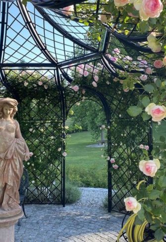 Internal view of the Schoenbrunn Wrought-Iron Gazebo by Classic Garden Elements with English roses and statue