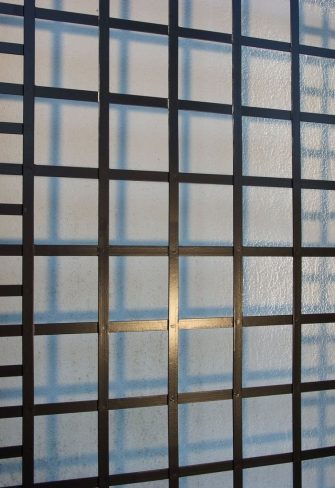 Close-up of the exclusive Poundbury Metal Wall Trellis by Classic Garden Elements casting shadows on the house wall