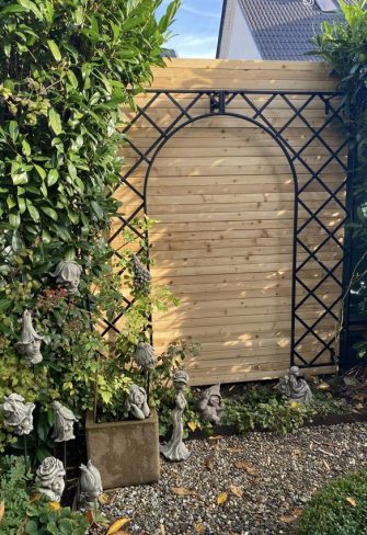 Concealing the neighbor's wooden hut with treillage trellis from Classic Garden Elements and roses